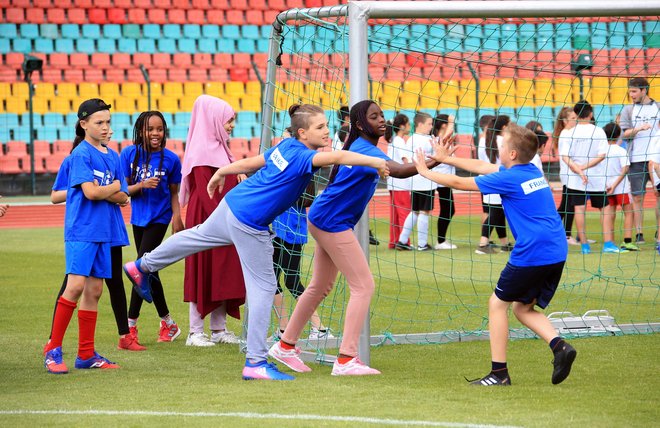 Kinder spielen gemeinsam Fußball bei einem Turnier, drei Kinder stehen vor einem Tor und sind im Spiel vertieft.