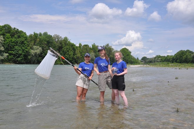 Drei junge Mädchen stehen mit Fischernetzen in einem Fluss