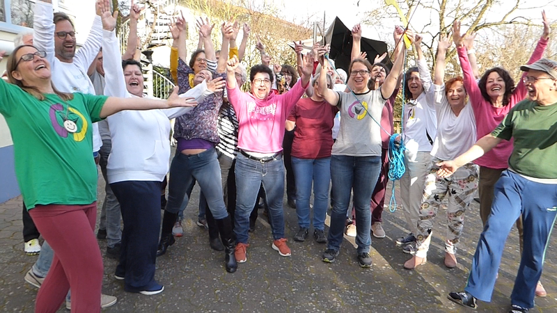 Lachtelefonist*innen mit Schnur werfen die Arme zum Jubel in die Höhe