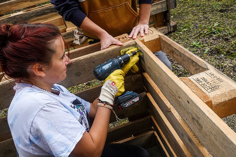 Eine Helferin befestigt Winkel in einem Hochbeet