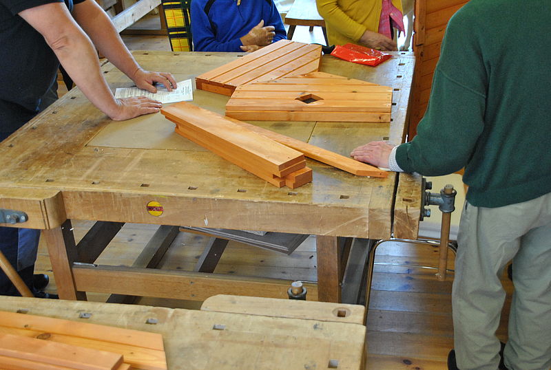 Ein Tisch in einer Werkstatt, auf dem Holz liegt.