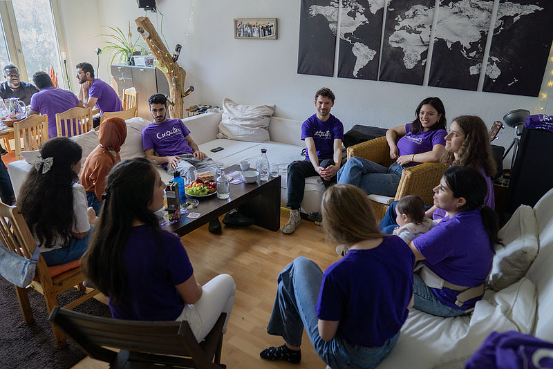 Menschen sitzen im Wohnzimmer im Kreis und diskutieren.