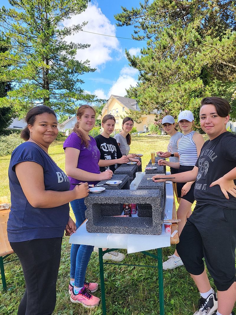 Jugendliche bemalen Gartenmauersteine