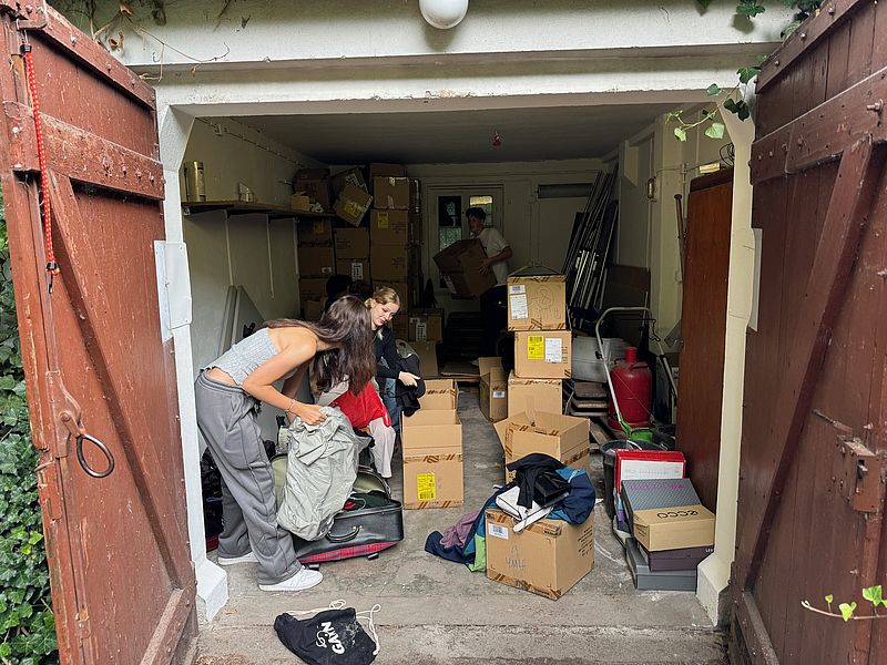 Schülerinnen sortieren in einer Garage Kleiderspenden
