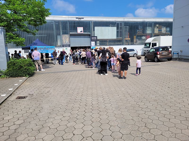 Menschen stehen vor einer großen Halle und möchten ein Fahrrad von Westwinderwerben