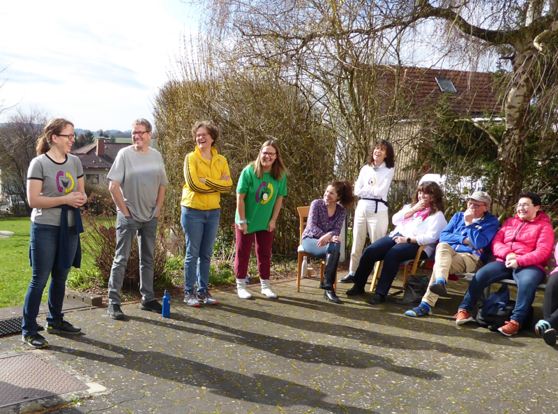 Lachtelefonist*innen stehen und sitzen auf einem Balkon