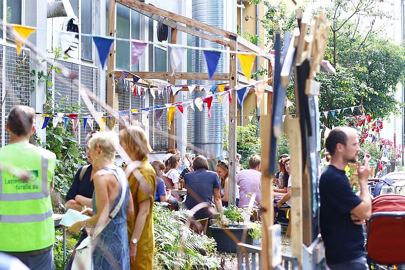 Kinder stehen in einem Naschgarten und schauen die Pflanzen an.