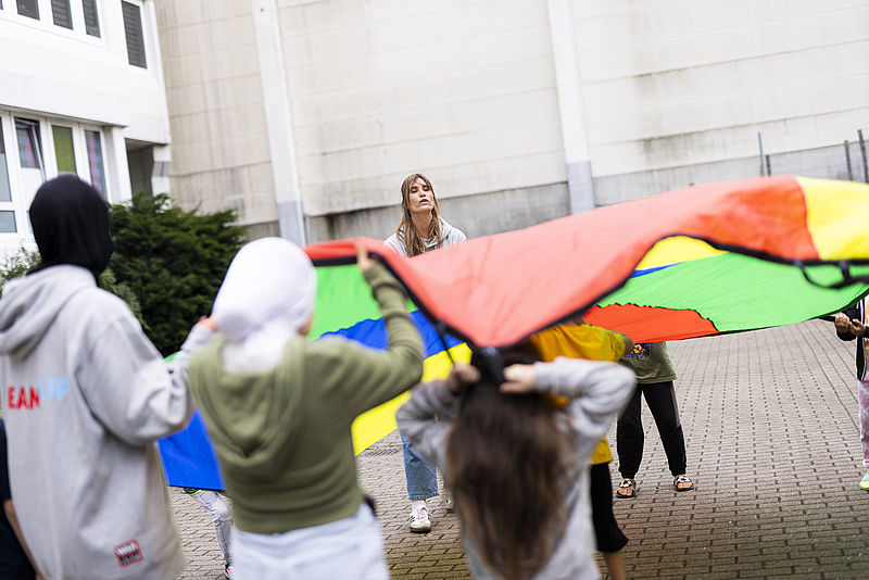 Kinder und Erwachsene bilden einen Kreis.