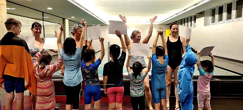 Kinder im Pool treten Wasser und machen sehr viel Welle